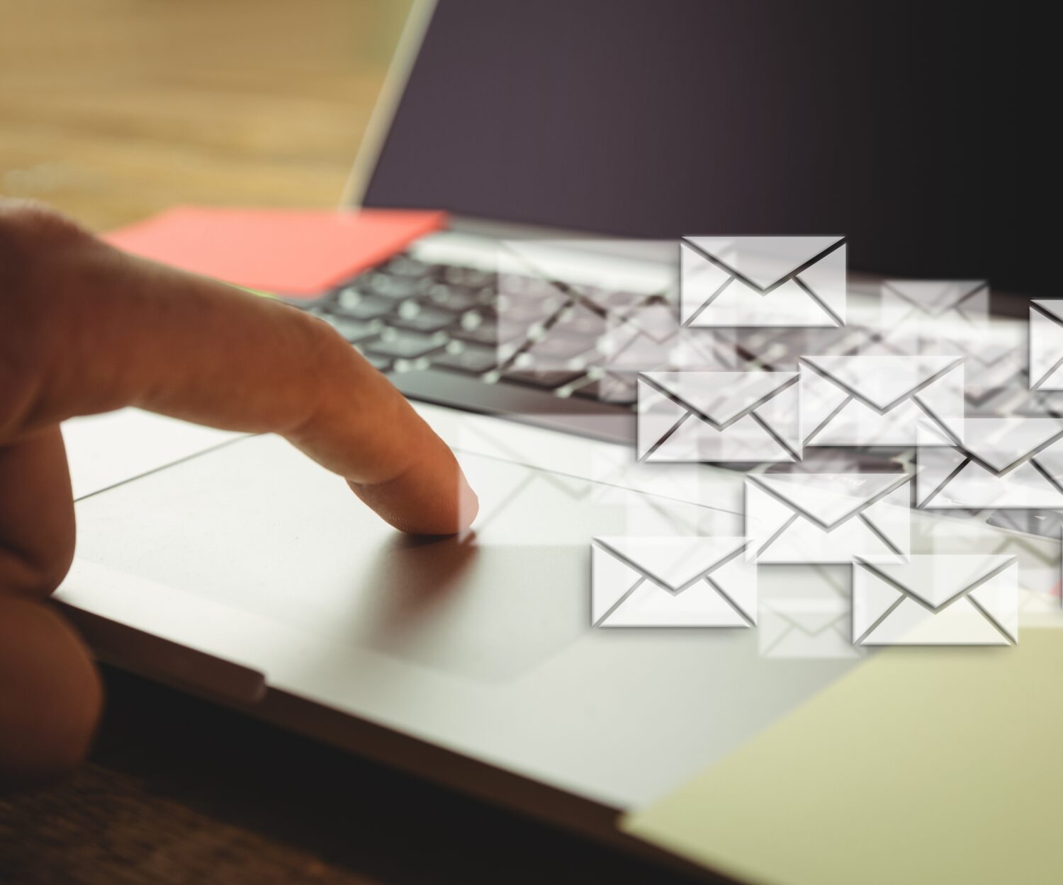 Composite image of hand using laptop put on a desk with letter icons